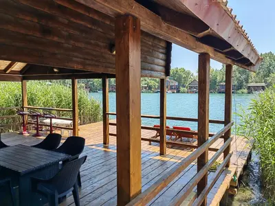 a wooden deck with a table and chairs on the water at River Escape Ada Bojana in Ulcinj