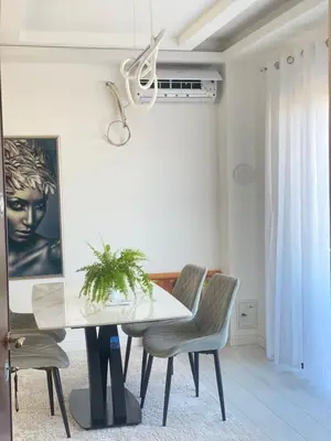 a dining room with a white table and chairs at Apartmani Hasanovic in Bar