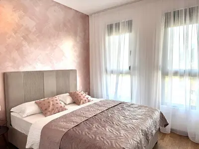 a bedroom with a bed with pink walls and windows at Apartment BAR M3A sea view in Bar