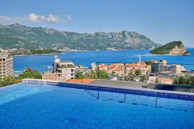 a large swimming pool with a view of a city at Como Vista Apartments in Budva