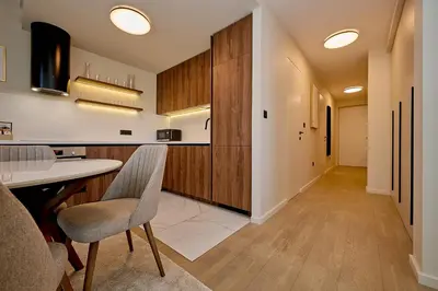 a kitchen with wooden cabinets and a table and chairs at Como Vista Apartments in Budva