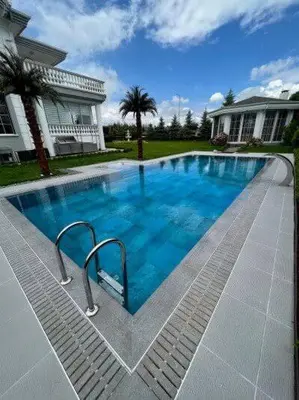 a large blue swimming pool in front of a house at Aurora suit in Podgorica