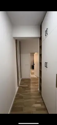 an empty room with a hallway with white walls and wood floors at Lux stan in Bar