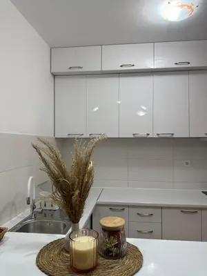a kitchen with white cabinets and a candle on a table at Peony in Budva