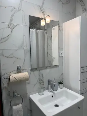 a white bathroom with a sink and a mirror at Peony in Budva