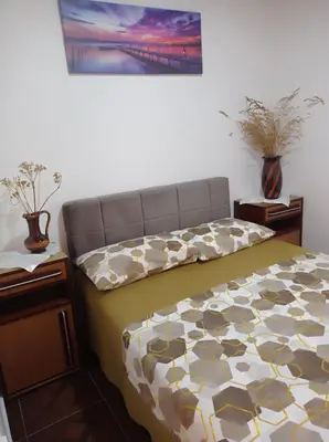 a bedroom with a bed with a comforter and two tables at Montanica in Virpazar