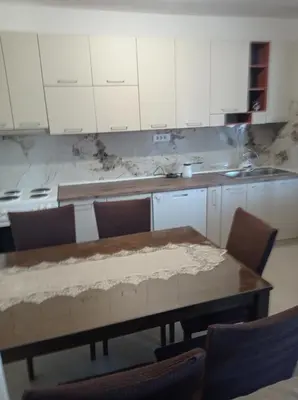 a kitchen with a wooden table and white cabinets at Montanica in Virpazar