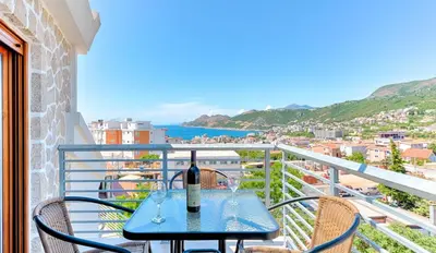 a table with a bottle of wine on a balcony at Lotos - stan 310 in Dobra Voda