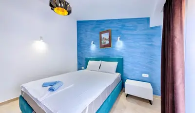 a bedroom with a white bed and a blue wall at Lotos - stan 310 in Dobra Voda