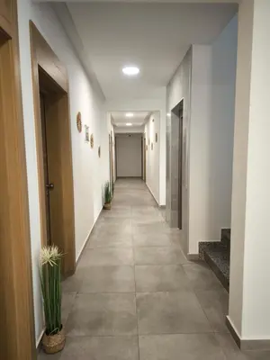 a hallway with white walls and a long hallway with plants at Bienvenue chez nous studio in Ulcinj