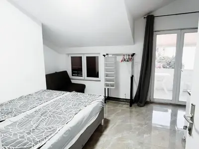 a bedroom with a bed and a chair and a window at Lalic House Budva in Budva