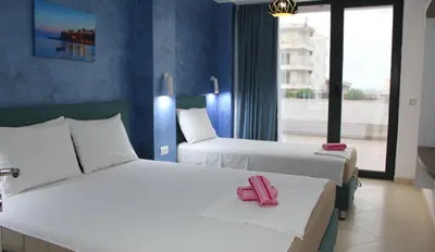 two beds in a hotel room with two pink slippers on them at Lotos - stan 106 in Dobra Voda