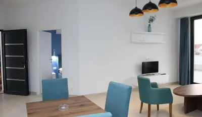 a living room with a table and blue chairs at Lotos - stan 106 in Dobra Voda