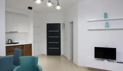 a living room with blue chairs and a flat screen tv at Lotos - stan 212 in Dobra Voda