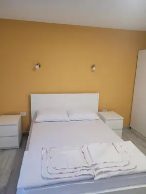 a bedroom with a white bed with two night stands at Apartmani Alternativa in Biserna Obala