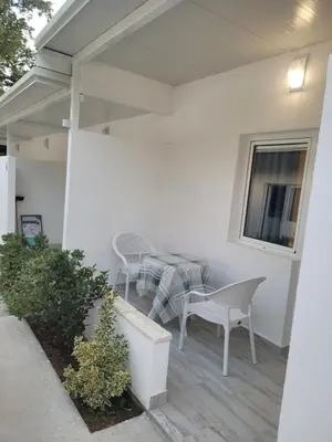a patio with a table and chairs and a window at Apartmani Alternativa in Biserna Obala