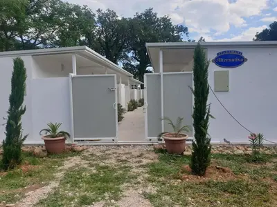 a white house with plants in front of it at Apartmani Alternativa in Biserna Obala