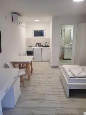 a white room with a table and a kitchen at Apartmani Alternativa in Biserna Obala