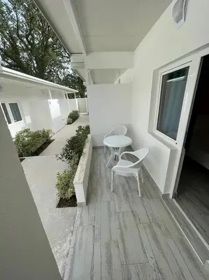 a patio with two chairs and a table and a window at Apartmani Alternativa in Biserna Obala