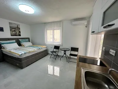 a bedroom with a bed and a table and a sink at Студия в Добра Вода in Dobra Voda