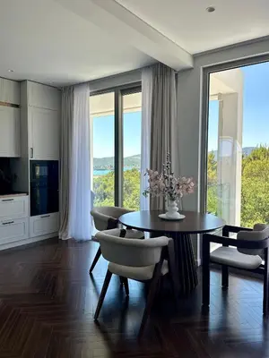 a dining room with a table and chairs and windows at Nika in Tivat