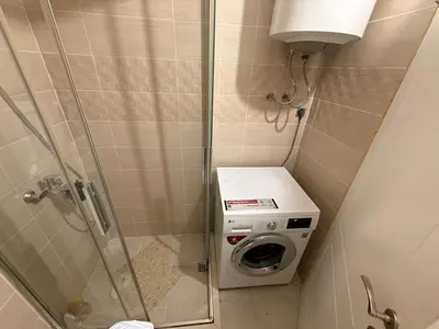 a bathroom with a shower with a washing machine at Stan na dan BUDVA in Budva