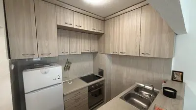 a kitchen with wooden cabinets and a white refrigerator at Stan na dan BUDVA in Budva