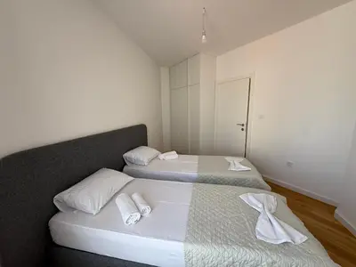 two beds in a small room with towels on them at Lux Apartman Rafailovici in Rafailovici