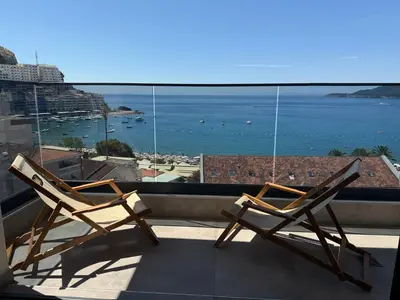 two chairs on a balcony with a view of the ocean at Lux Apartman Rafailovici in Rafailovici