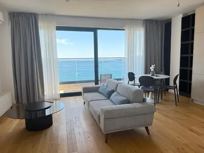 a living room with a couch and a view of the ocean at Lux Apartman Rafailovici in Rafailovici