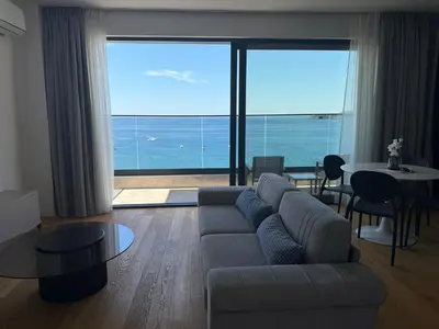 a living room with a couch and a view of the ocean at Lux Apartman Rafailovici in Rafailovici