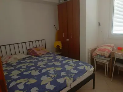 a bedroom with a bed and a table and a cabinet at Inna Apartment near the Sea in Petrovac na Moru