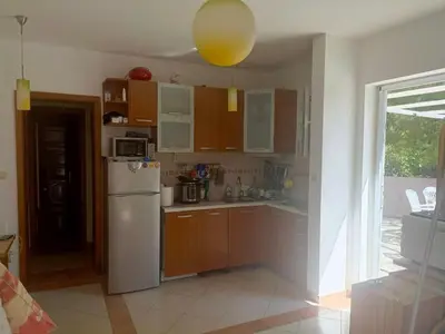 a kitchen with wooden cabinets and a white refrigerator at Inna Apartment near the Sea in Petrovac na Moru