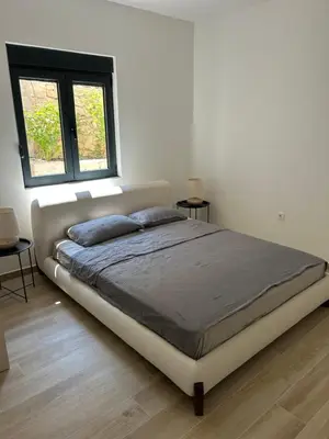 a large bed in a white room with two windows at Villa Richard in Sutomore