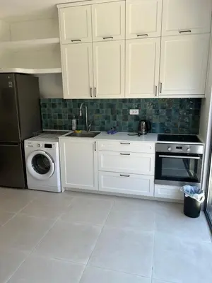 a kitchen with white cabinets and a washing machine at Villa Richard in Sutomore