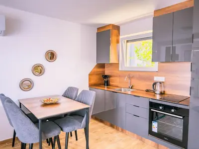 a kitchen with a table and chairs and a sink at TaNa's Apartments in Donji Štoj