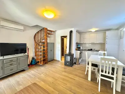 a living room with a dining room table and a kitchen at Beachfront Holiday Home Rafailovici in Becici