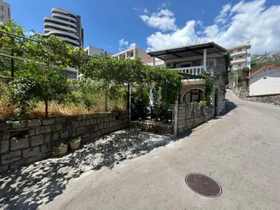 a building with a fence with ivy on it at Beachfront Holiday Home Rafailovici in Becici