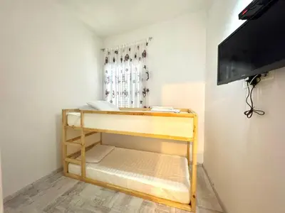 a small room with a bunk bed and a television at Beachfront Holiday Home Rafailovici in Becici