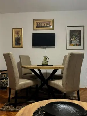 a dining room with a table with chairs and a television at Apartman M5 in Cetinje