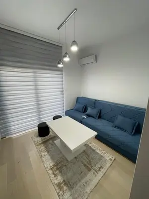 a living room with a blue couch and a white table at Nata 25 in Becici
