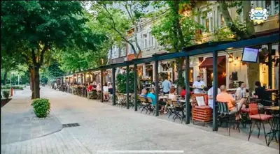a street with tables and chairs and people sitting at restaurants at Bokeska apartment in Podgorica
