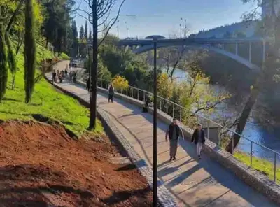 people walking on a sidewalk next to a river at Bokeska apartment in Podgorica