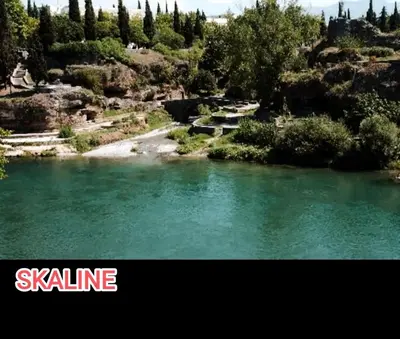 a river with green water and trees in the background at Bokeska apartment in Podgorica