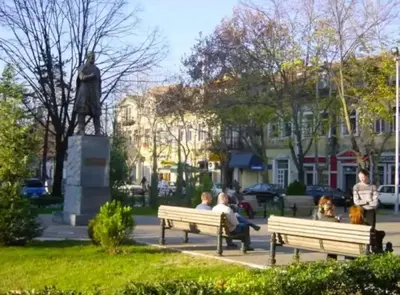 people sitting on benches in a park with a statue at Bokeska apartment in Podgorica