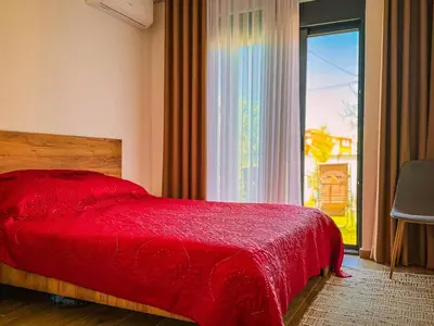 a bedroom with a red bed and a large window at TaNa's Villa in Donji Štoj