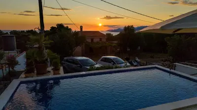 a swimming pool in a yard with a sunset in the background at Casa del Sol Zagora in Zagora