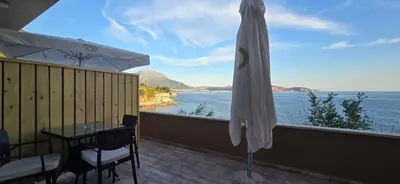 a balcony with a table and an umbrella and the ocean at Beachfront Blue Panorama in Bar