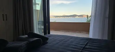 a bedroom with a bed and a view of the ocean at Beachfront Blue Panorama in Bar