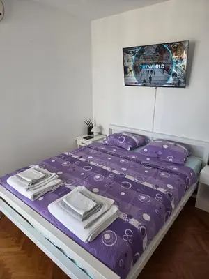 a bed with a purple comforter and towels on it at Laurel Apartment See View in Budva